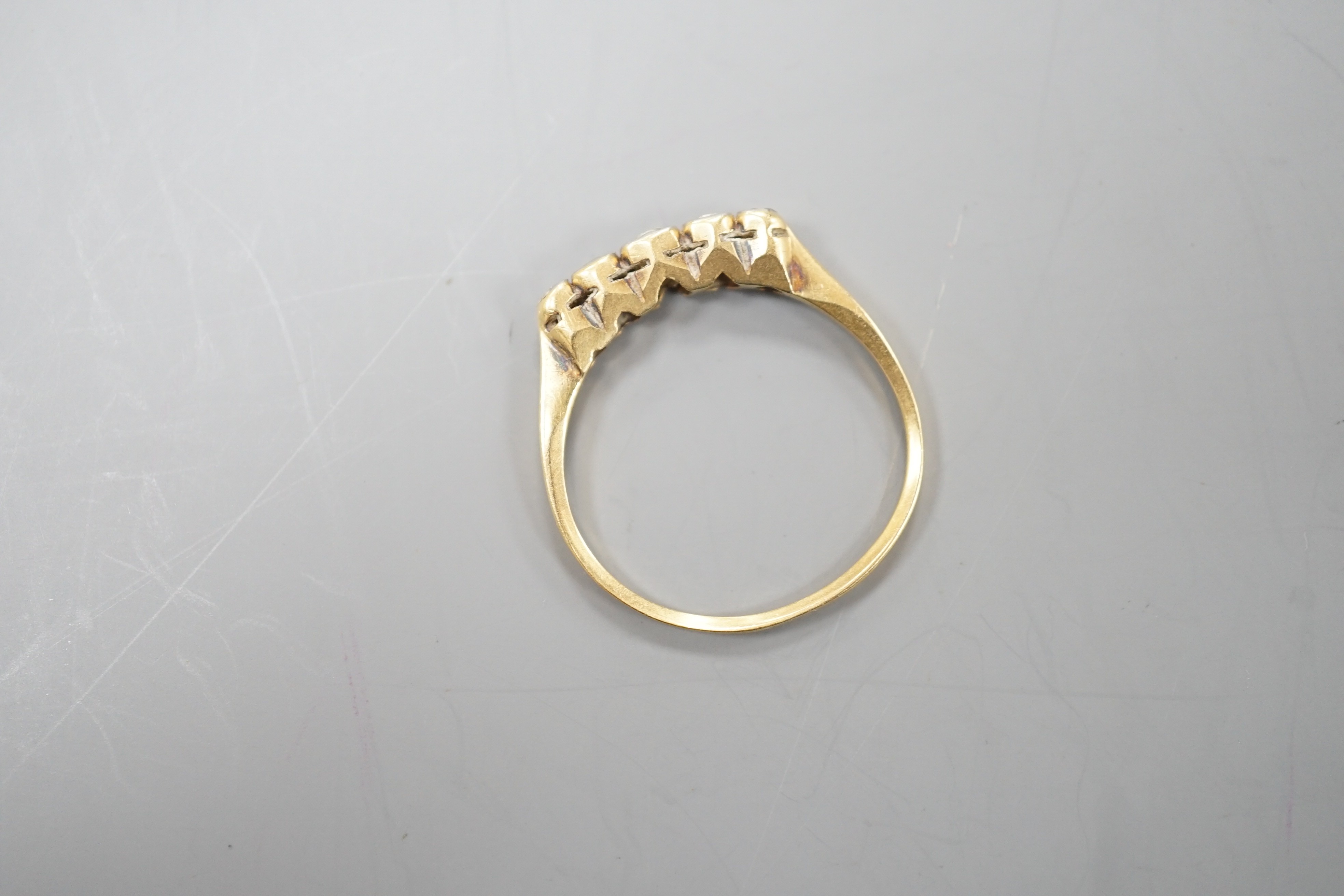 A yellow metal and graduated collet set five stone diamond half hoop ring, size O, gross weight 1.7 grams.